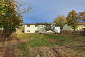 Rear view of house featuring a lawn, solar panels, and a wooden deck