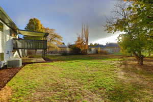 View of yard with central air condition unit and a wooden deck