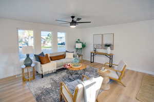 Living room featuring ceiling fan, a textured ceiling, and light hardwood / wood-style flooring