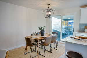 Dining room with a textured ceiling, light wood-type flooring, and an inviting chandelier