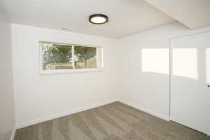 Carpeted spare room featuring a textured ceiling