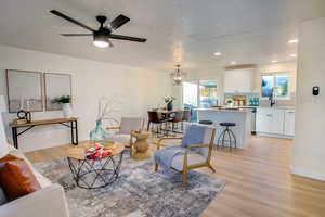 Living room featuring a textured ceiling, ceiling fan with notable chandelier, light hardwood / wood-style floors, and sink