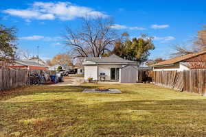 Rear view of house featuring a lawn, a patio area, a fire pit, and a shed