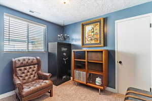 Sitting room featuring a notable chandelier, carpet floors, and a textured ceiling