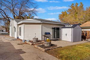 Rear view of property with a shed and a patio