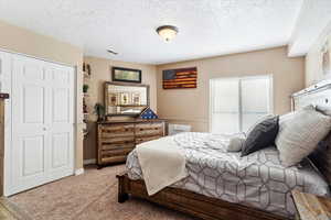 Bedroom with carpet flooring, a textured ceiling, and a closet