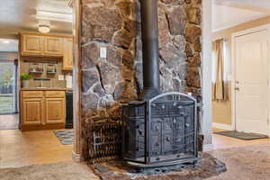 Details featuring a wood stove, black dishwasher, tasteful backsplash, hardwood / wood-style floors, and a textured ceiling