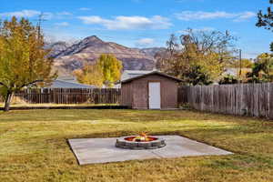 View of yard with a mountain view, a patio, a shed, and an outdoor fire pit