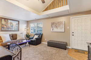 Living room with a textured ceiling, light wood-type flooring, ceiling fan, and lofted ceiling