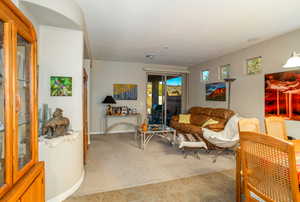 from dining room/ entry looking at view of carpeted living room with sliding glass door to backyard.