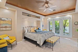 Carpeted bedroom featuring ceiling fan, access to exterior, a textured ceiling, and a tray ceiling