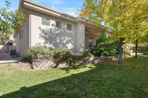 View of property exterior featuring ceiling fan, cooling unit, and a lawn