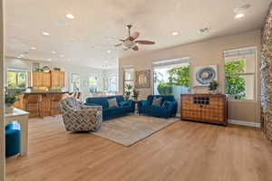 Living room with a textured ceiling, light wood-type flooring, and ceiling fan