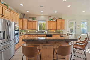 Kitchen featuring a center island, a kitchen breakfast bar, light wood-type flooring, appliances with stainless steel finishes, and tasteful backsplash