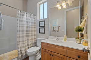 Full bathroom featuring shower / bath combo, vanity, and toilet