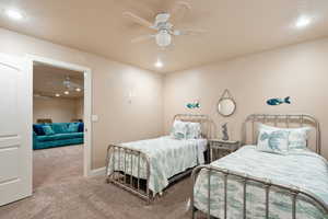 Bedroom featuring ceiling fan, light colored carpet, and a textured ceiling