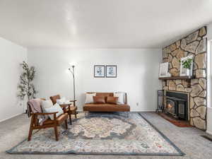 Carpeted living room with a wood stove and a textured ceiling