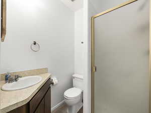 Bathroom featuring hardwood / wood-style flooring, vanity, toilet, and a shower with door