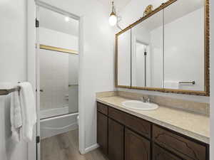 Full bathroom featuring vanity, hardwood / wood-style flooring, toilet, and enclosed tub / shower combo