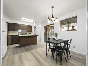 Dining space with a chandelier, a textured ceiling, and light wood-type flooring