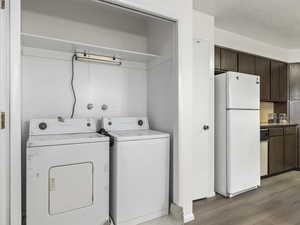 Laundry room featuring light hardwood / wood-style flooring, washer and dryer, and a textured ceiling