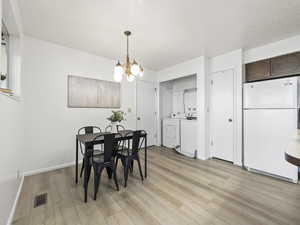 Dining space featuring washer and dryer, light hardwood / wood-style floors, and an inviting chandelier