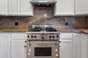 Kitchen featuring stainless steel range, white cabinets, and extractor fan