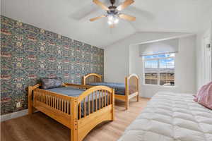 Bedroom with hardwood / wood-style flooring, vaulted ceiling, and ceiling fan