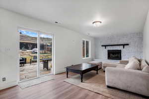 Living room with a stone fireplace and light hardwood / wood-style flooring