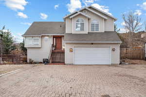 View of front of property featuring a garage and central air condition unit