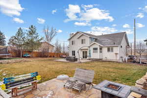 Back of property featuring a lawn, a patio, a fire pit, and a trampoline