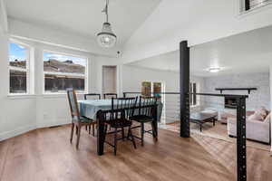 Dining space with a chandelier, hardwood / wood-style floors, a stone fireplace, and a wealth of natural light