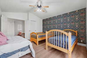 Bedroom with hardwood / wood-style floors, a closet, vaulted ceiling, and ceiling fan