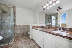 Bathroom featuring toilet, vanity, and walk in shower