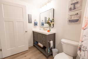 Bathroom with hardwood / wood-style floors, vanity, and toilet