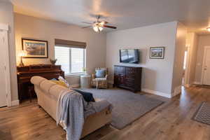 Living room with light hardwood / wood-style floors and ceiling fan