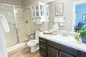 Bathroom featuring hardwood / wood-style floors, vanity, toilet, and walk in shower