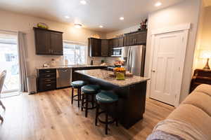 Kitchen featuring dark brown cabinets, a kitchen island, stainless steel appliances, and a breakfast bar area