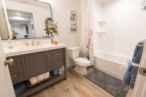 Full bathroom featuring wood-type flooring, vanity, toilet, and shower / tub combo with curtain