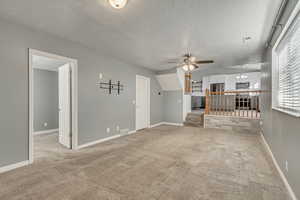 Living room featuring carpet, ceiling fan, and a textured ceiling