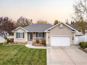 Ranch-style house with covered porch, a garage, and a yard