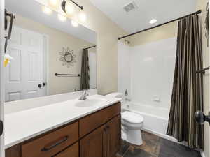 Full bathroom with vanity, toilet, and shower / bath combo with shower curtain