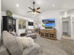 Living room with ceiling fan, carpet floors, and vaulted ceiling