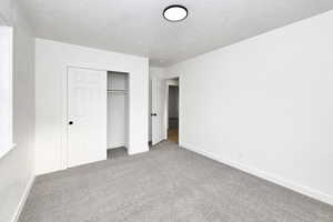 Unfurnished bedroom featuring a textured ceiling, carpet floors, and a closet