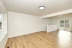 Spare room with a textured ceiling and light wood-type flooring