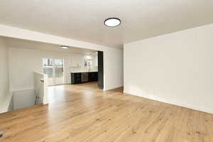 Unfurnished living room featuring light hardwood / wood-style flooring and a textured ceiling