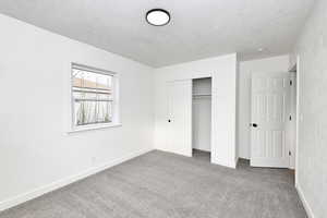 Unfurnished bedroom featuring a textured ceiling, carpet floors, and a closet