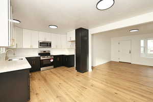 Kitchen with white cabinets, light wood-type flooring, sink, and appliances with stainless steel finishes