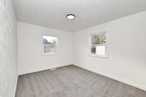 Carpeted empty room featuring a textured ceiling