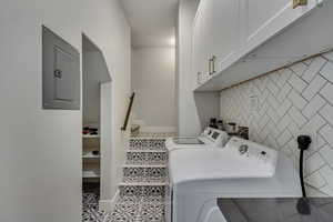 Laundry area with cabinets, separate washer and dryer, tile walls, electric panel, and light tile patterned flooring